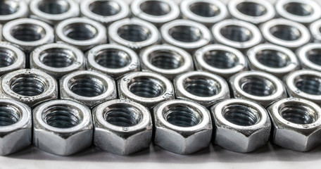 Metal texture. Background of identical nuts with thread. Selective focus.