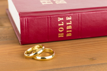 Gold wedding rings on wooden table and red bible book - Powered by Adobe