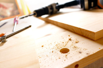 Carpentry work. Drilling holes in the board. Tool in the backgro