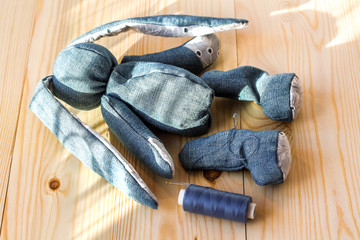 Handmade jean bunny layed on the wood working table with sewing accessories.