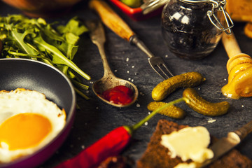 Table with food in breakfast or lunch: omelette, cabbage, oil, chili, ketchup, arugula, onion, garlic, noodles, cucumber, coffee, biscuits, orange, bread and butter