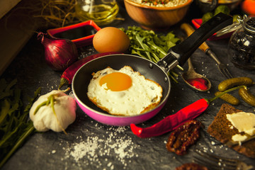 Table with food in breakfast or lunch: omelette, cabbage, oil, chili, ketchup, arugula, onion, garlic, noodles, cucumber, coffee, biscuits, orange, bread and butter
