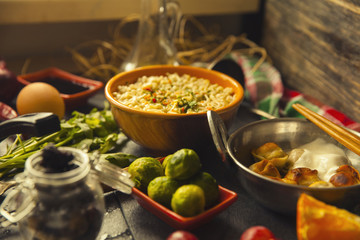 Table with food in breakfast or lunch: omelette, cabbage, oil, chili, ketchup, arugula, onion, garlic, noodles, cucumber, coffee, biscuits, orange, bread and butter