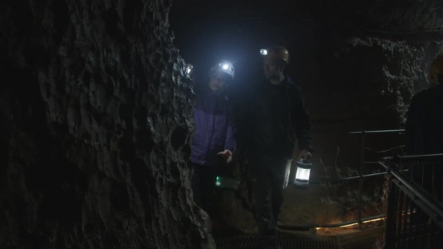  Team of geologists exploring underground cave, discussing rock formation