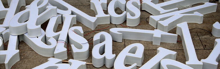 Three-dimensional letters of white letters intended for making advertisements are scattered on the floor