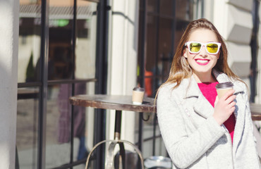 Outdoor portrait of young woman with long blonde hair with coffee to go
