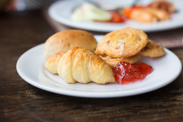 Fresh Croissants with strawberry jam on rustic wooden background. Selective focus