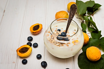 Healthy breakfast with yogurt with blueberries and muesli   and peach on white background.