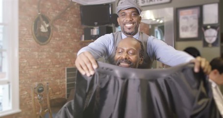  Friendly barber working on a customer in traditional retro barber shop. 