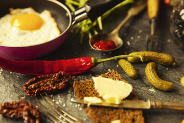 Table with food in breakfast or lunch: omelette, cabbage, oil, chili, ketchup, arugula, onion, garlic, noodles, cucumber, coffee, biscuits, orange, bread and butter