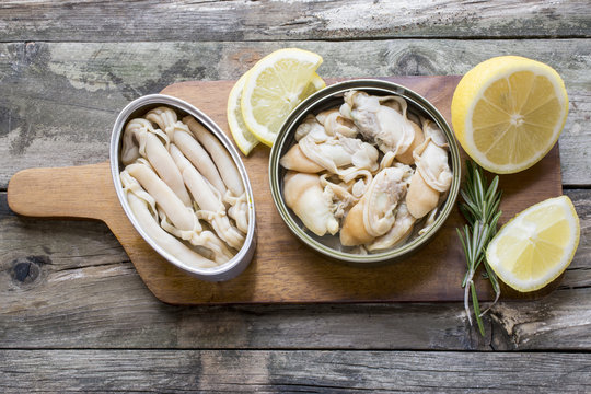 Can of preserved with clams on a plate on a rustic wooden table