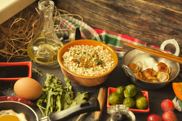 Table with food in breakfast or lunch: omelette, cabbage, oil, chili, ketchup, arugula, onion, garlic, noodles, cucumber, coffee, biscuits, orange, bread and butter