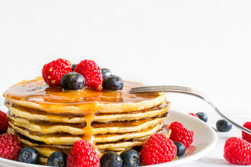 delicious pancakes with berries and caramel sauce with fork