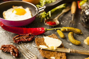 Table with food in breakfast or lunch: omelette, cabbage, oil, chili, ketchup, arugula, onion, garlic, noodles, cucumber, coffee, biscuits, orange, bread and butter