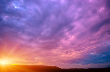 Photo of a violet sunset with clouds and sun