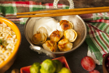 Table with food in breakfast or lunch: omelette, cabbage, oil, chili, ketchup, arugula, onion, garlic, noodles, cucumber, coffee, biscuits, orange, bread and butter