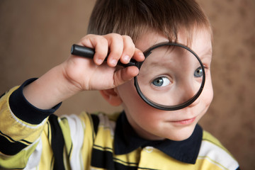 a little boy looks through a magnifying glass (large eyes of a child through a magnifying glass)