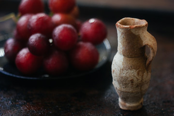 Small clay jug behind the grapes