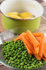 Peeled potatoes with cooked green peas and carrot