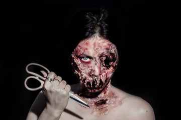  horrible scary zombie girl with a scissors on black background with copyspace