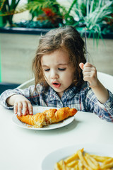 Cute little girl having breakfast with the croissant in a restaurant.
