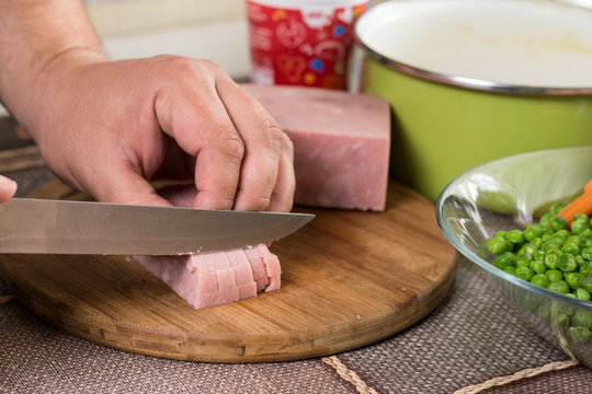 Cook chef slicing ham with ingredients in the background
