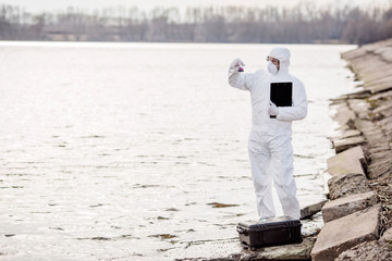 Scientist or biologist wearing protective uniforms examining the liquid contents of a test tube. .