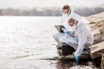 Scientists or biologists wearing protective uniforms working together on water analysis. .
