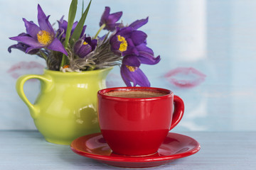 red cup of coffee, bouquet of spring flowers and stamped lips on background