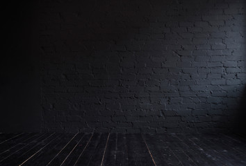 Dark interior with black brick wall and black wooden floor