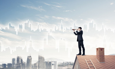 Engineer man standing on roof and looking in spyglass. Mixed med