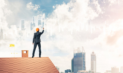 Man architect draw silhouette of modern city on blue sky. Mixed 