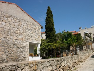 Alte Fassade eines Bauernhaus und Mauer aus Naturstein und Bruchstein vor blauem Himmel mit...