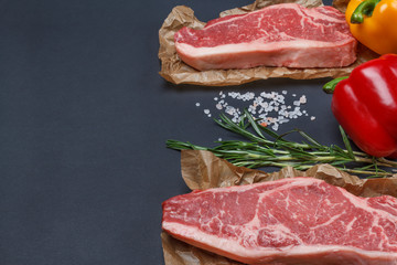 New York striploin Steak with pepper, salt and rosemary backgr