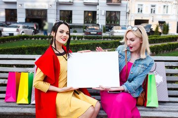 happy people concept - beautiful women with shopping bags . Hold a white nameplate for your text