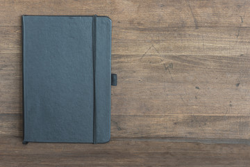 black copybook on wooden background with space for text