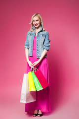 Shopping woman holding shopping bags on pink background