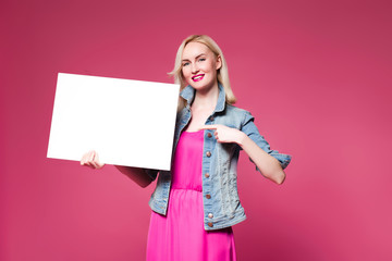 Shopping woman holding shopping bags on pink background . Holds a white nameplate for your text