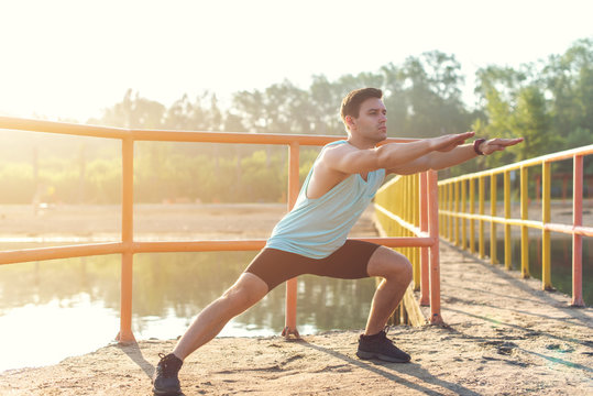 Fitness man athlete warming up legs before jogging outdoors