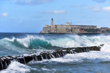 A view over a stormy sea from the Malecon with Morro Castle in the background in Havana, Cuba