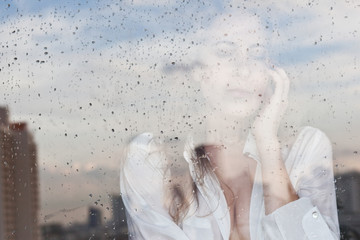 Melancholy reflection of the girl in the window