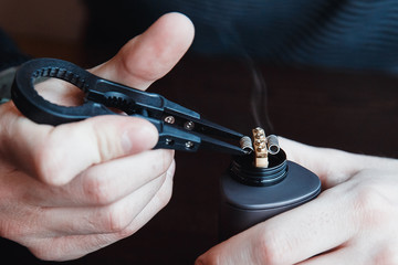 male master installs a coil. Spiral for electronic evaporator and cigarette. Vape, vaping. Firing a...