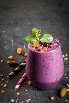 Healthy food. Dietary breakfast, snack. Berry smoothies with granola, black currant, blueberries and nuts almonds, decorated with mint. On a dark concrete table with ingredients, copy space