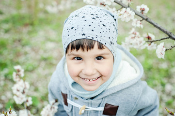 Half-length portrait of a little boy in grey hat looking up and smiling