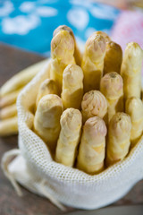 Spring season - fresh white asparagus in burlap sack on granite plank background