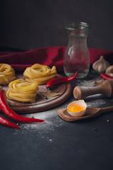 Raw homemade pasta with flour and spices on the rustic background.
