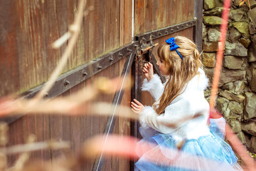 Side view of an little beautiful girl in the scenery of Alice in Wonderland looking into the...