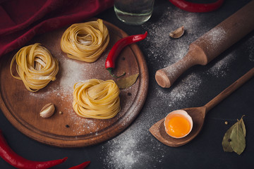 Raw homemade pasta with flour and spices on the rustic background.