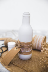 Homemade diy glass bottle. Scissors, burlap, handmade vase on a wooden table. Rustic style. DIY concept