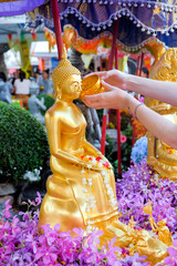 Fototapeta premium Close-up Tourist people pouring water (bathing) on Buddha statue in Songkran Festival (Thai New Year), Thailand